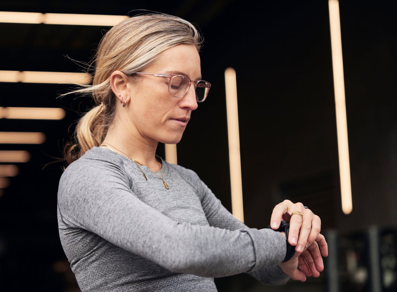 Woman checking her watch wearing rectangular, bourbon Cade eyeglasses