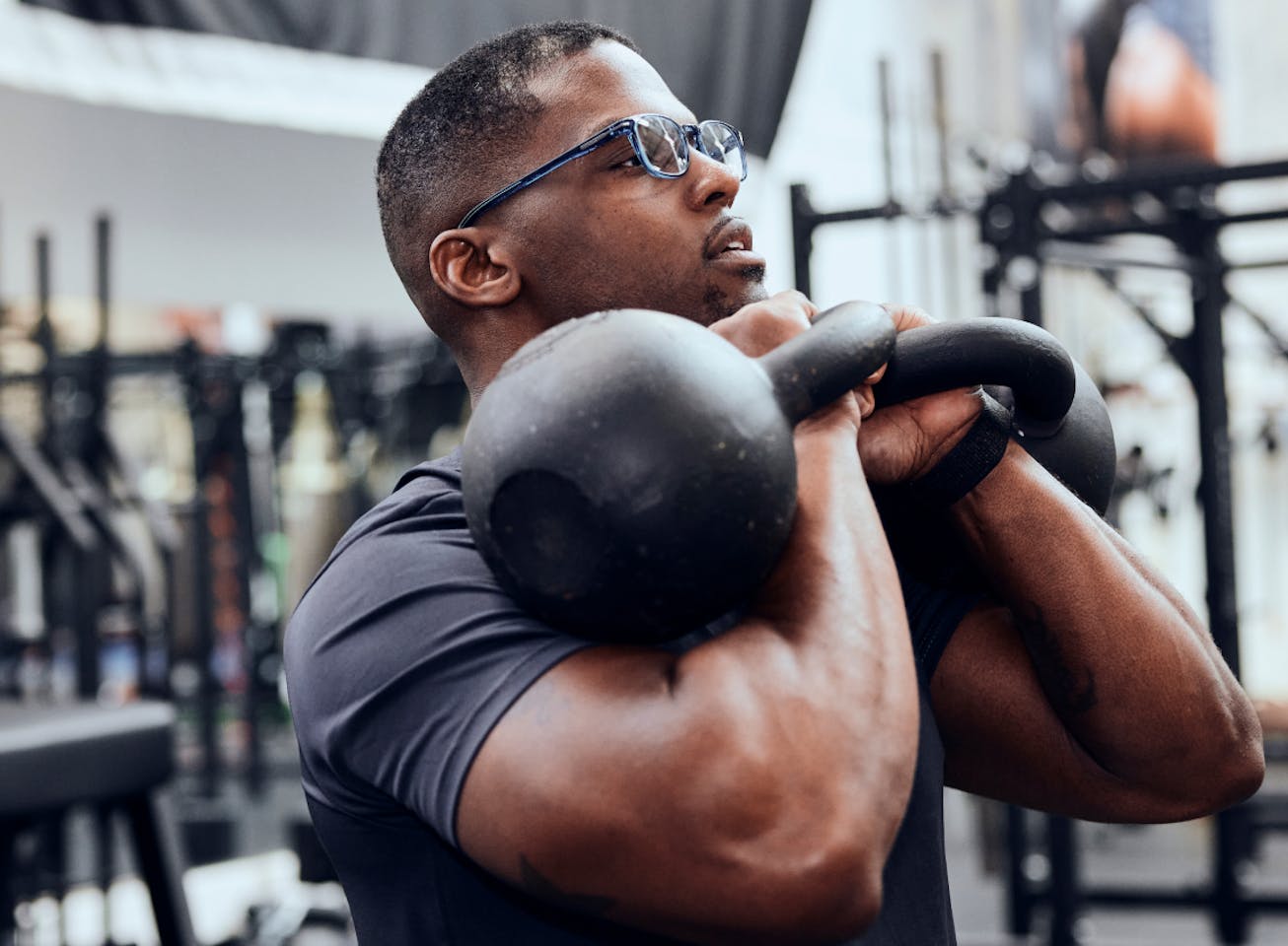 Man holding kettlebells wearing rectangular, crystal slate Cade eyeglasses