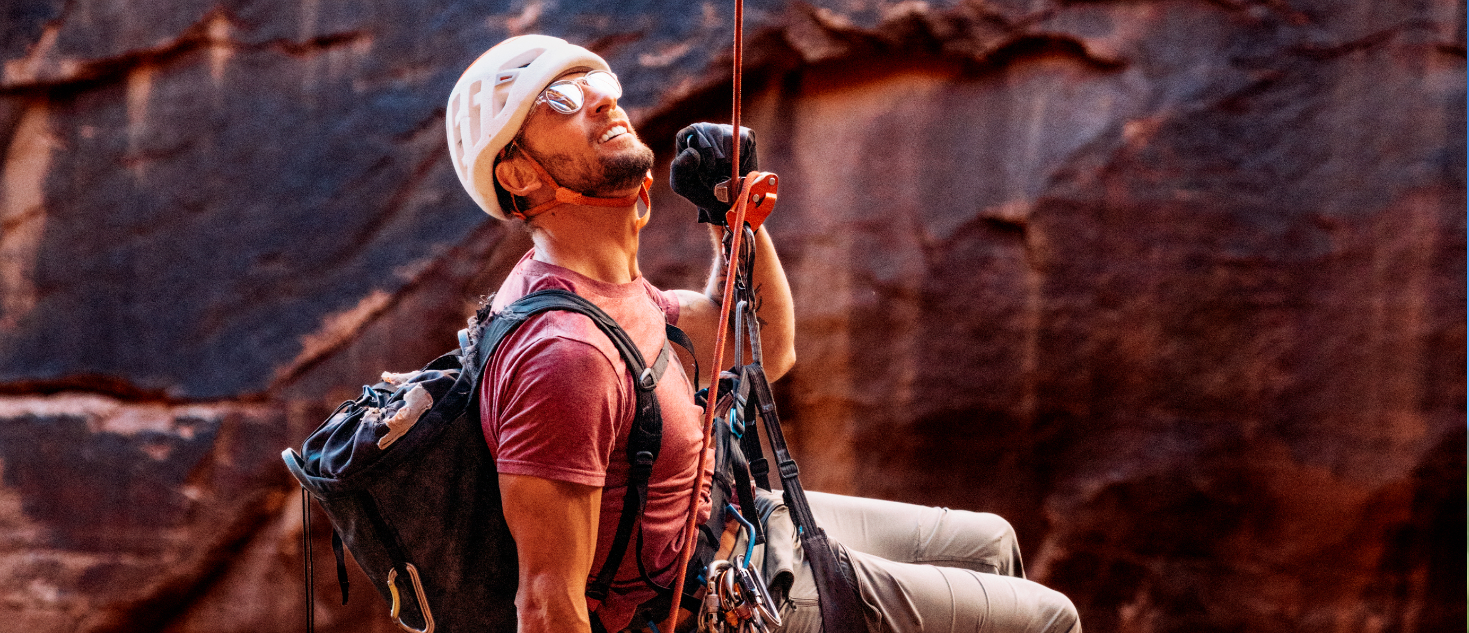 Man repelling down canyon wearing Oslo sunglasses