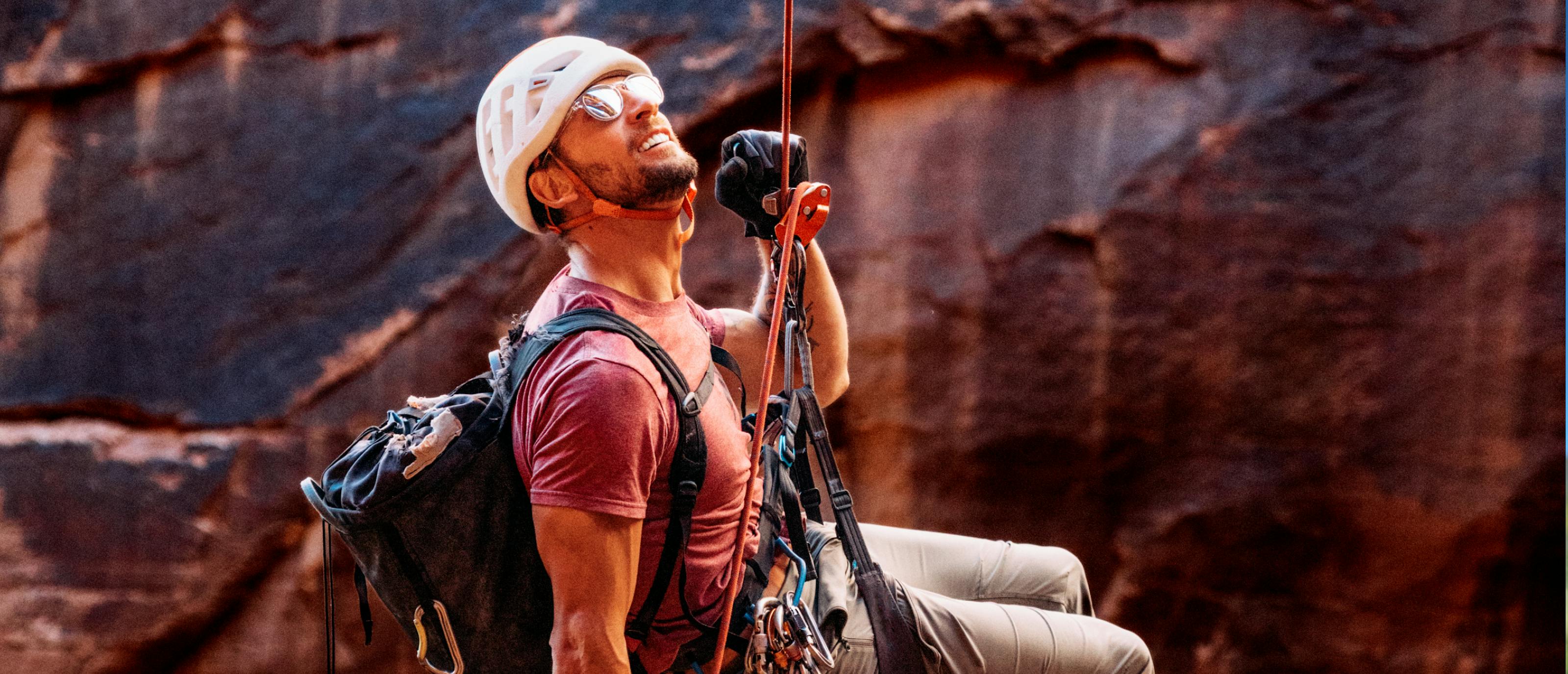 Man repelling down canyon wearing Oslo sunglasses