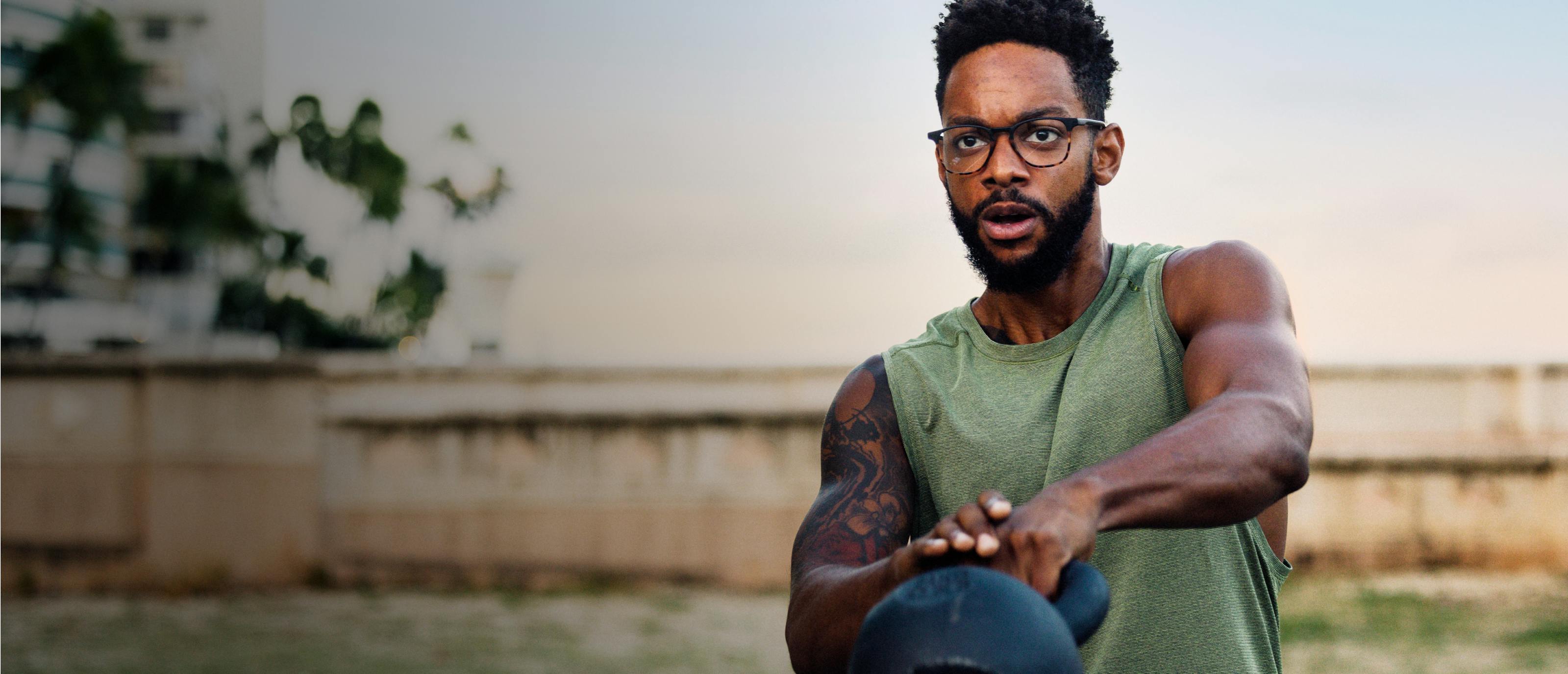 Man swinging kettlebell wearing square, campfire tortoise Hunter eyeglasses