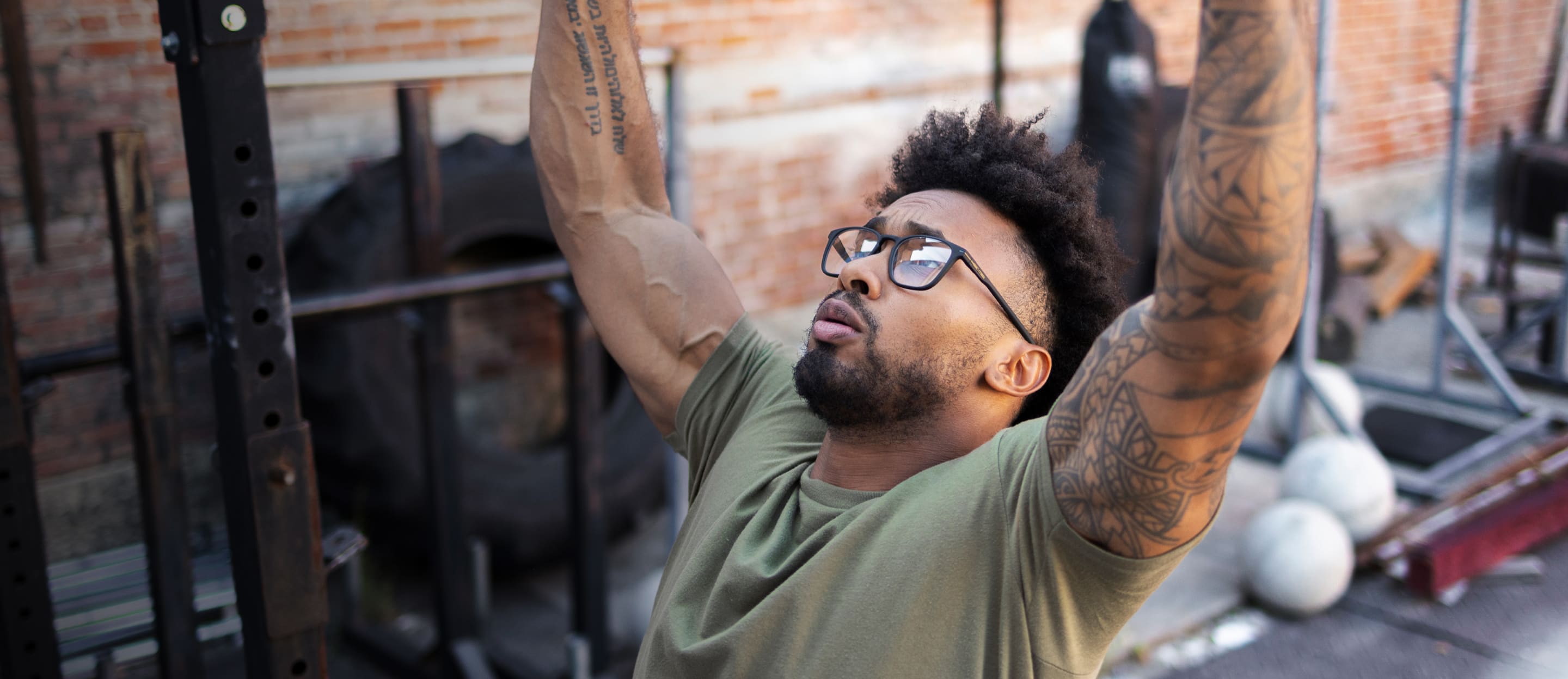 Man doing pull ups wearing rectangular, matte black Rory eyeglasses
