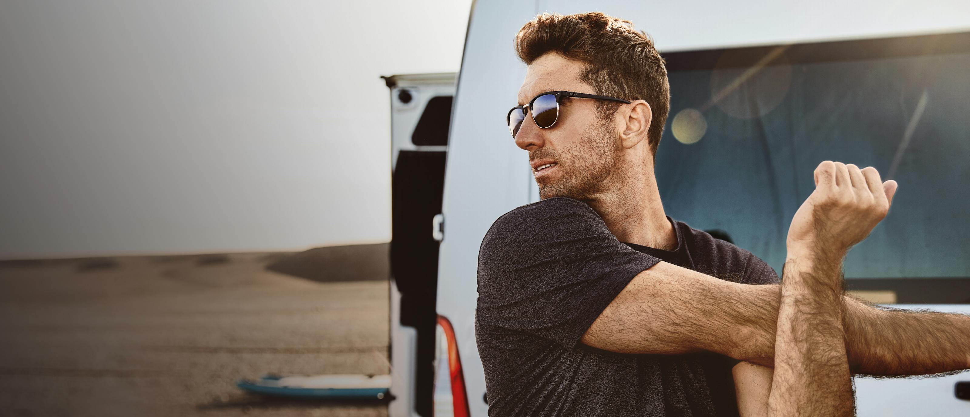 Man stretching in front of car wearing Cambridge sunglasses