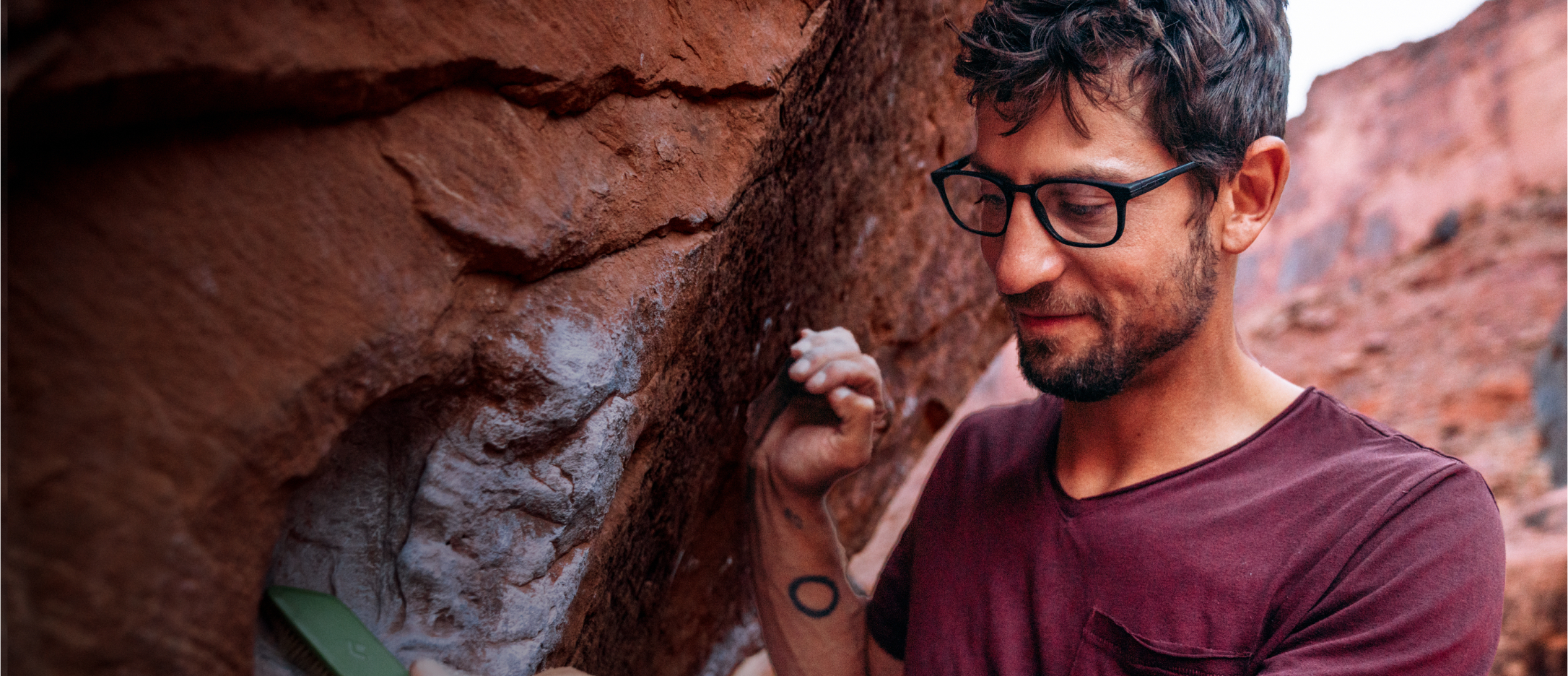 Man by a boulder wearing rectangular, matte black Cade eyeglasses