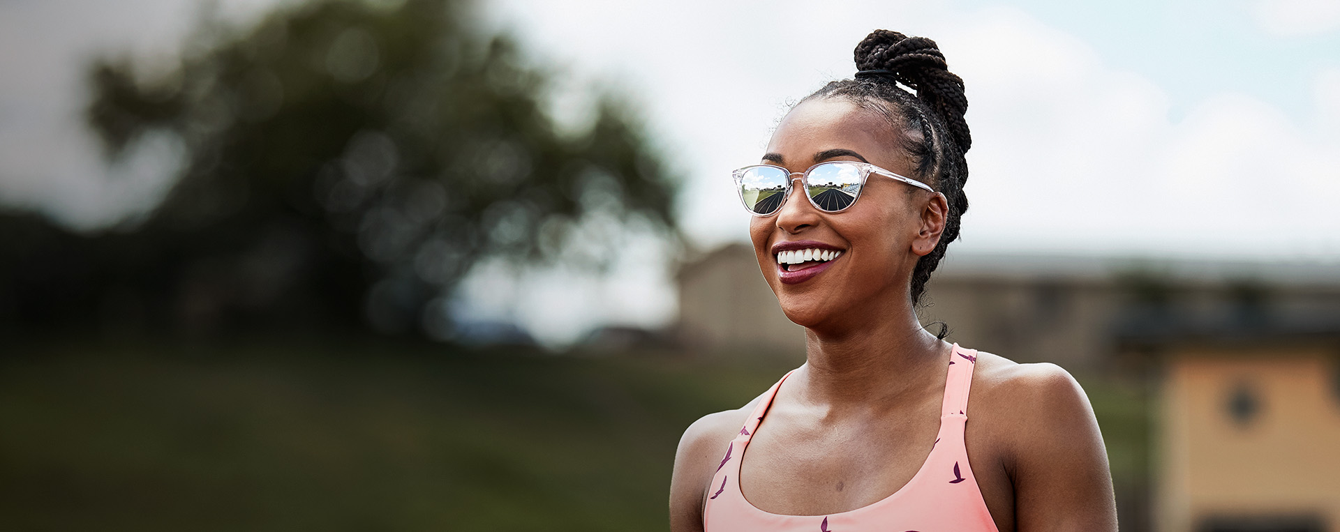 Woman smiling with the running track in the reflection of ROKA sunglaases