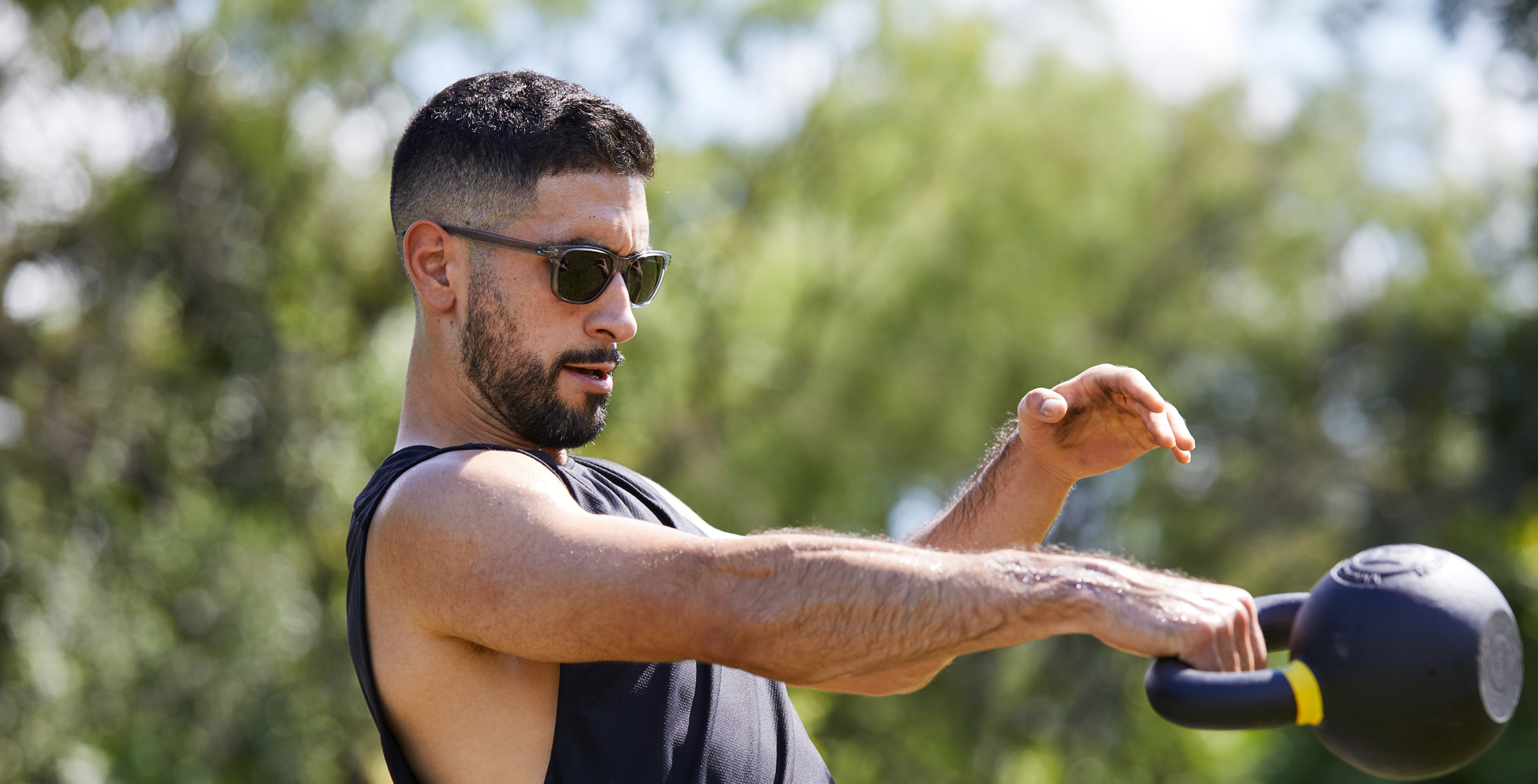 Man using kettlebell wearing Zilker sunglasses