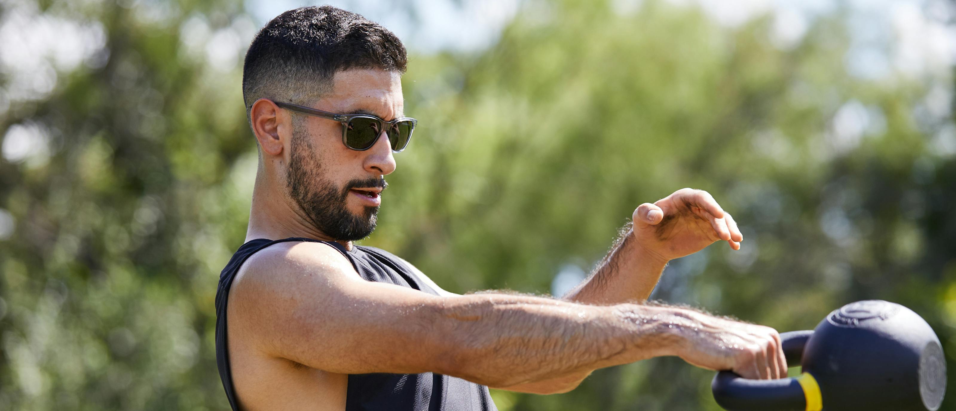 Man using kettlebell wearing Zilker sunglasses