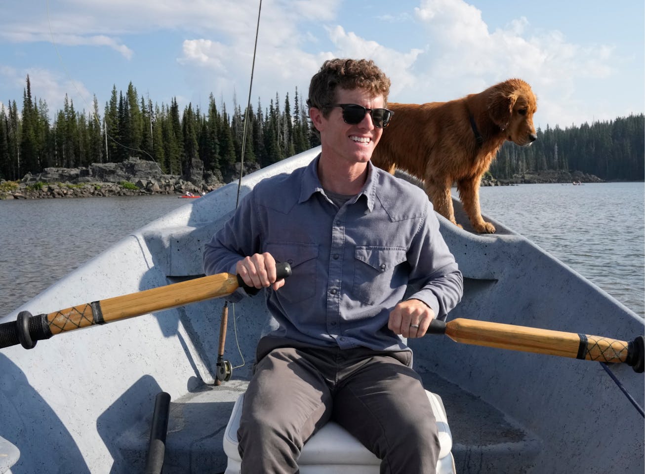 Man rowing boat with dog wearing Hunter sunglasses