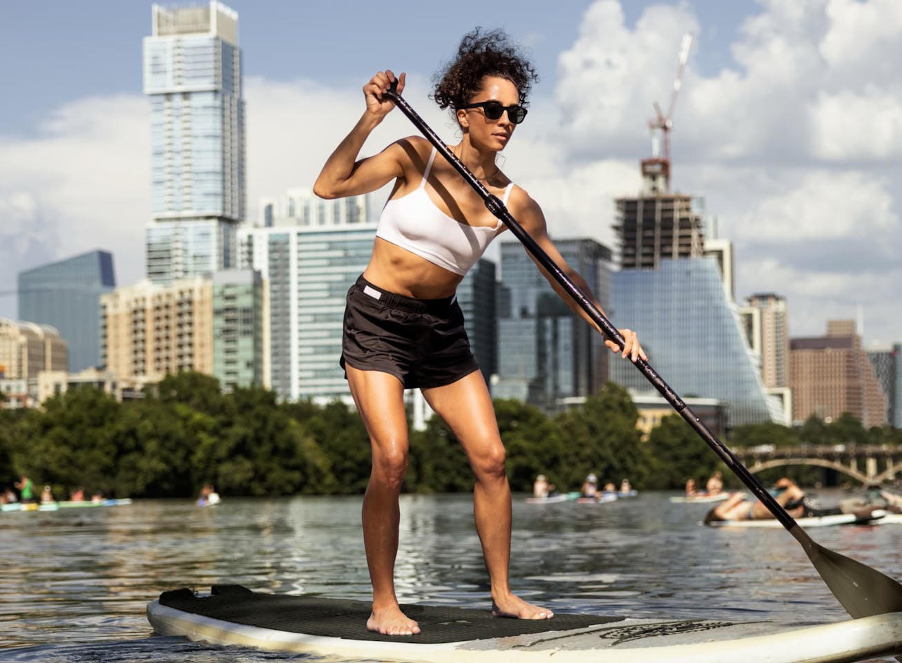 Woman paddleboarding in front of city skyline