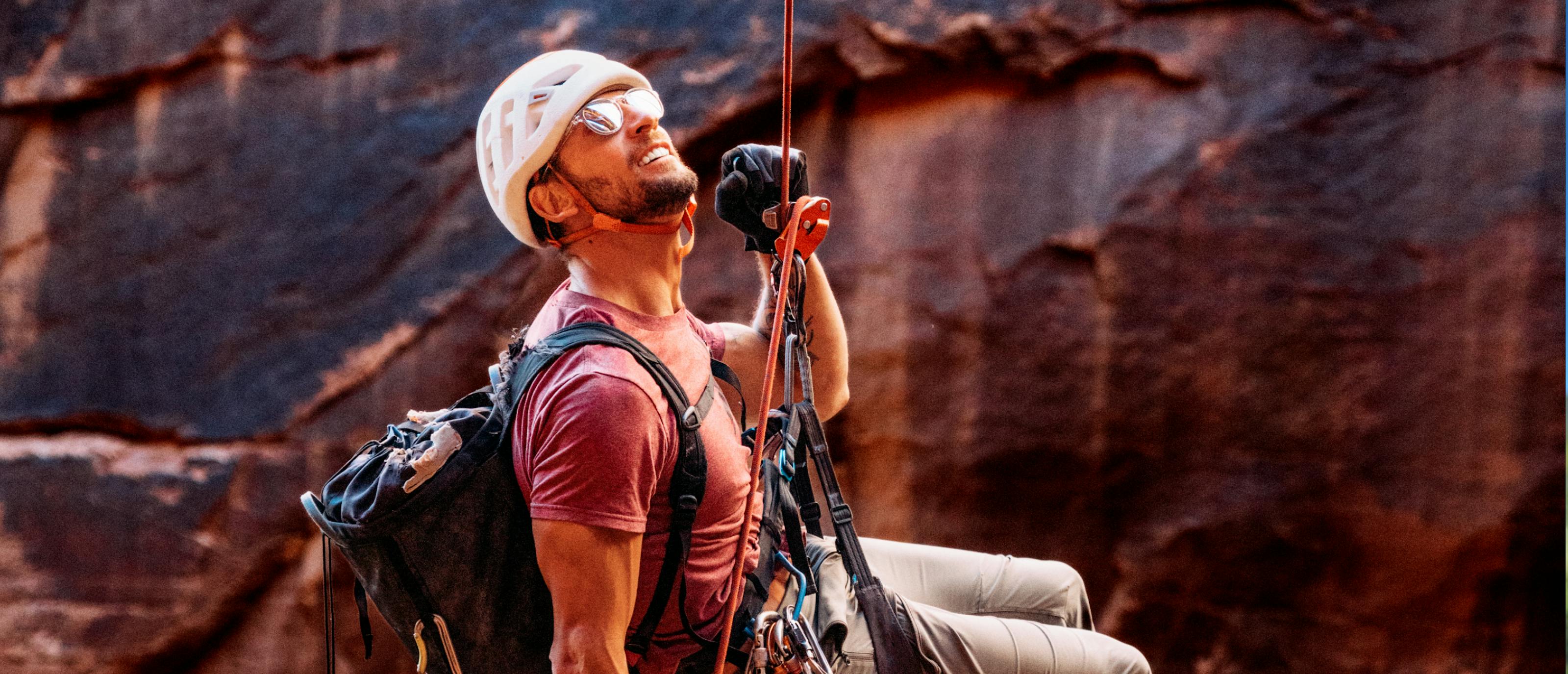 Man repelling down canyon wearing Oslo sunglasses