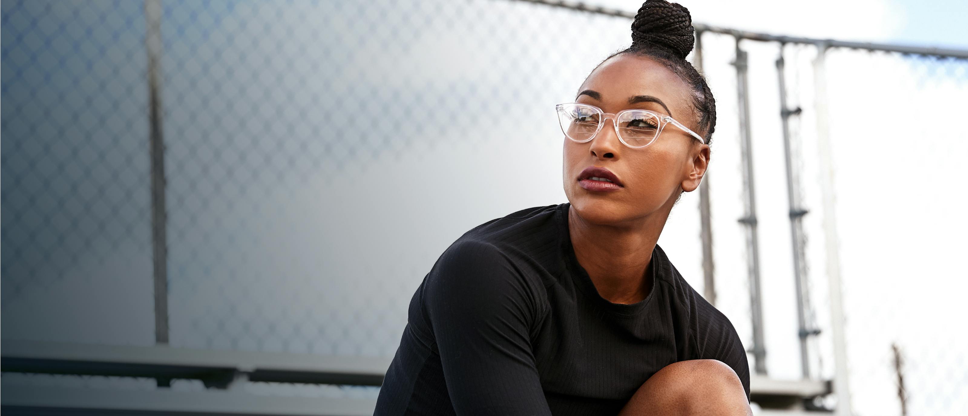 Woman sitting outside wearing cat eye shape, clear Lola eyeglasses