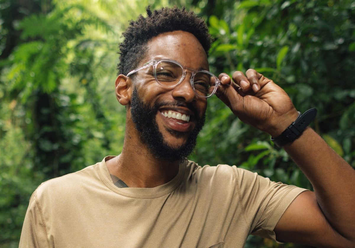 Man smiling fixing his round, clear frame Oslo eyeglasses