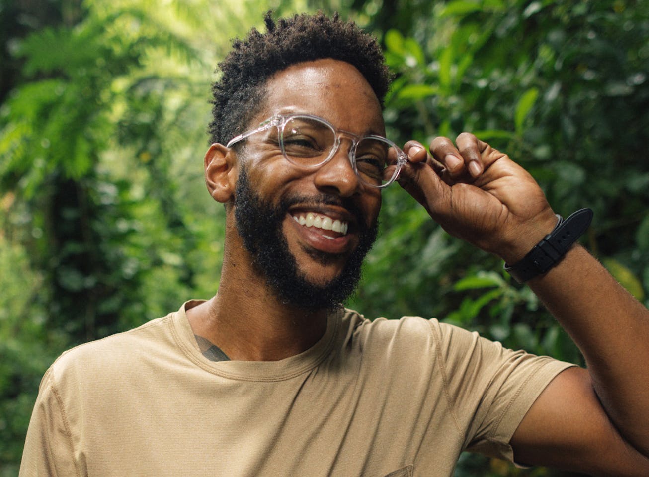 Man smiling fixing his round, clear frame Oslo eyeglasses