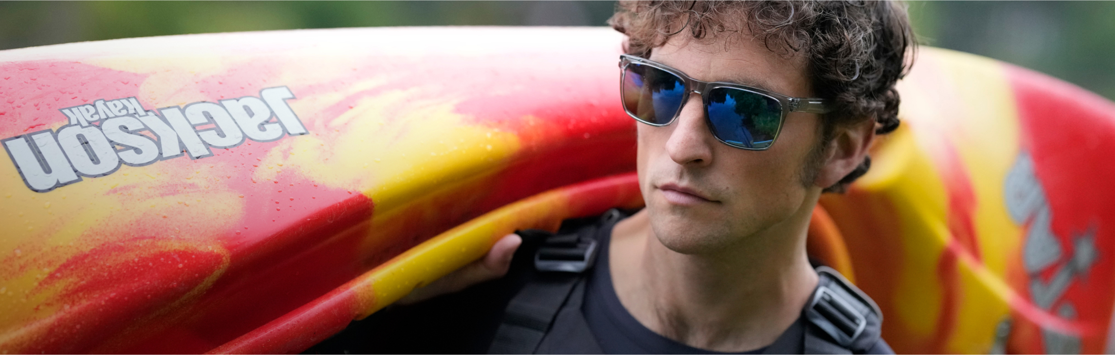 Man with kayak on shoulder wearing ROKA sunglasses