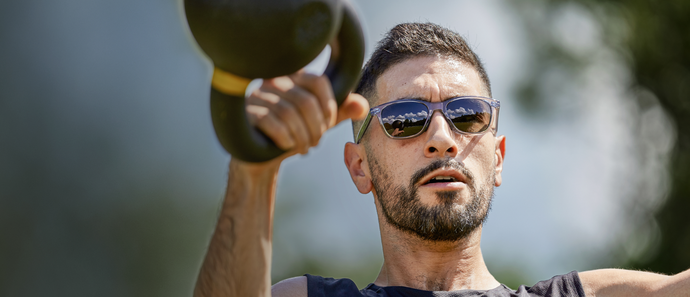 Man swinging kettlebell wearing Zilker sunglasses