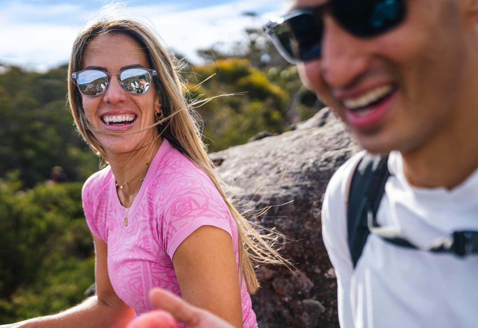 Woman in pink shirt hiking with man both wearing Hunter sunglasses