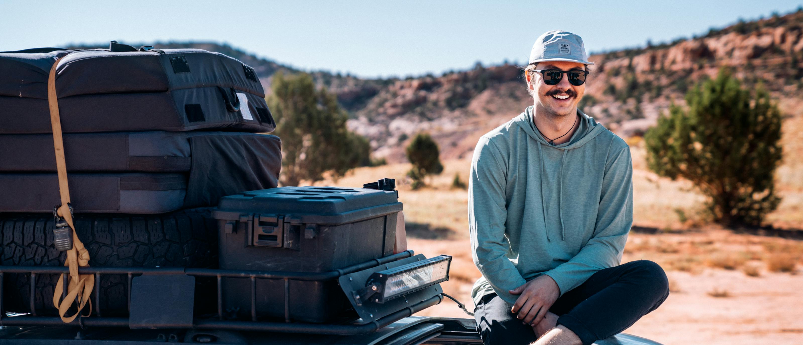 Man sitting on top of car wearing Hunter sunglasses
