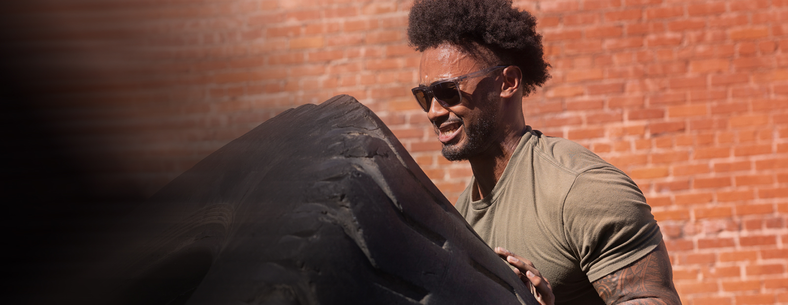 Man working out pushing tire in ROKA sunglasses