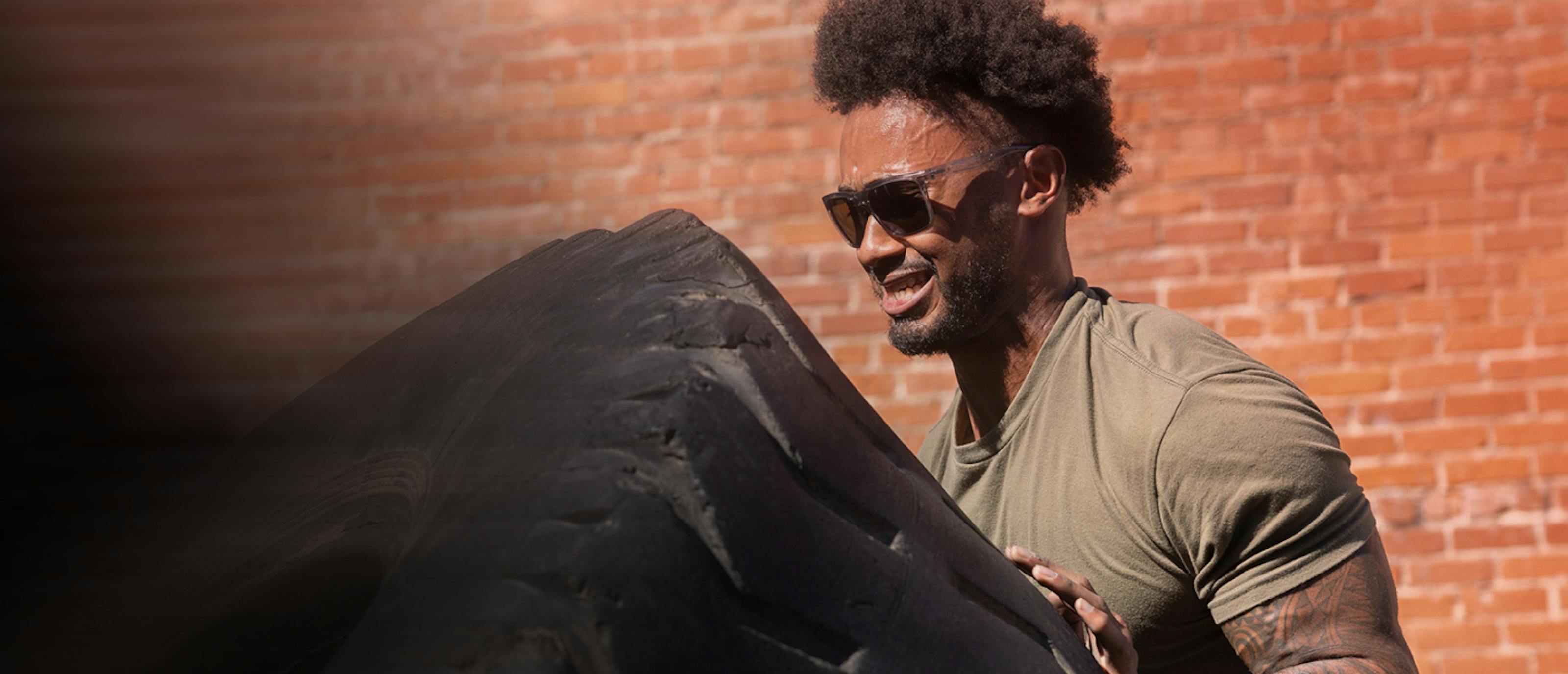 Man working out pushing tire in ROKA sunglasses