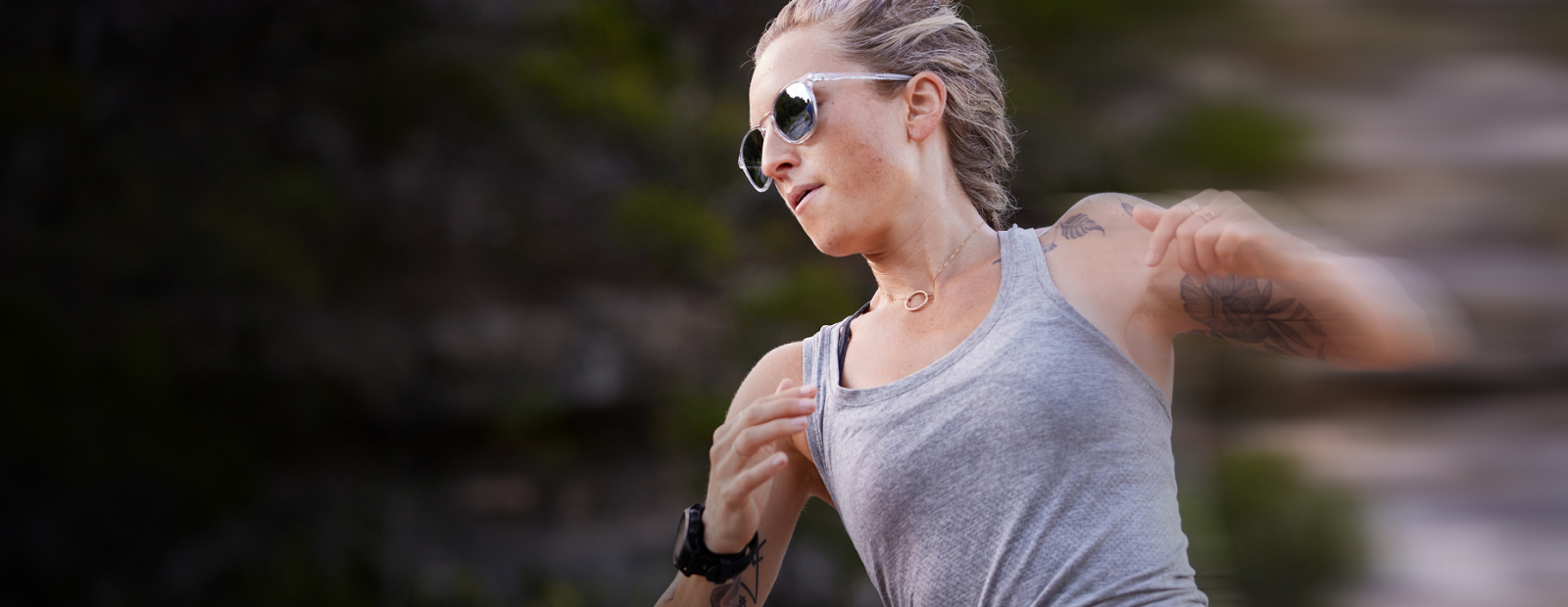 Woman running in grey tank top and ROKA sunglasses
