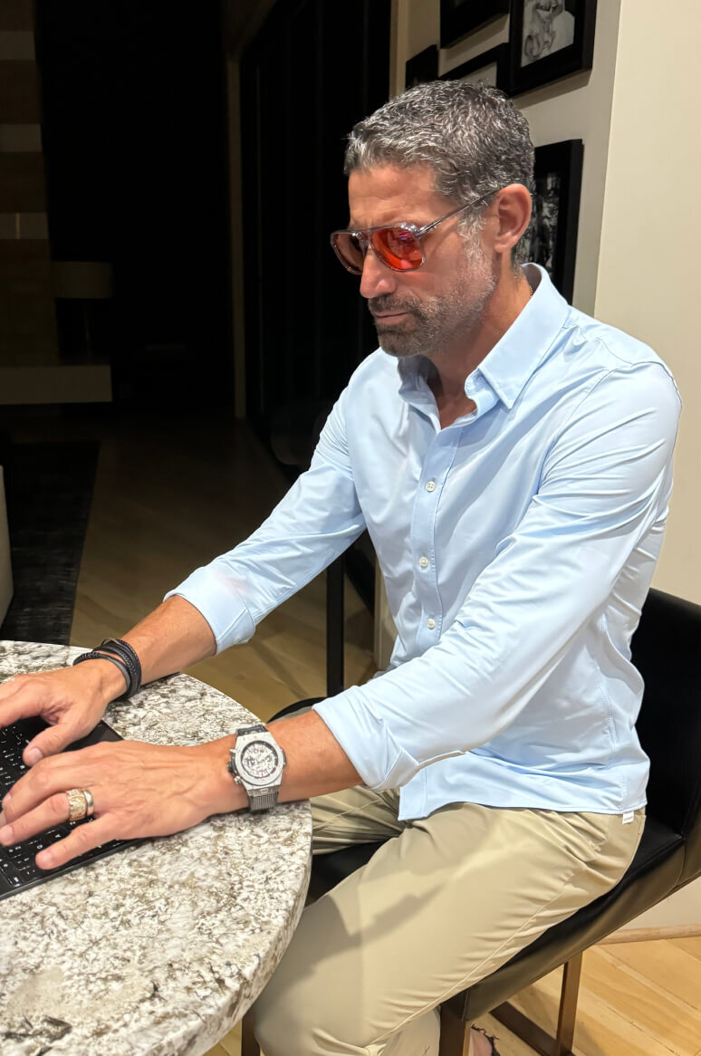 Man in blue shirt typing on keyboard in red lens glasses