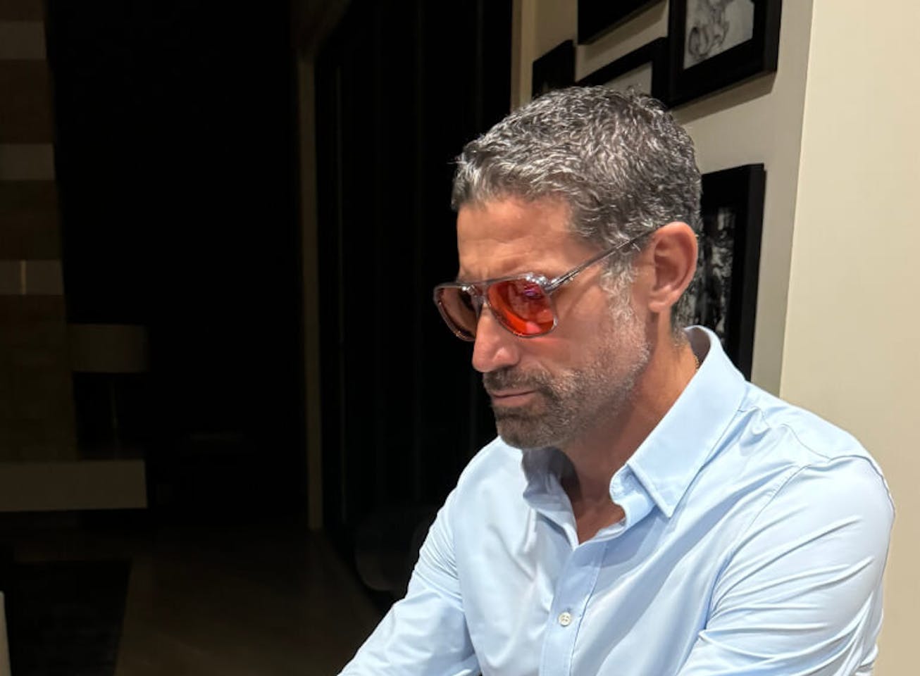 Man in blue shirt typing on keyboard in red lens glasses