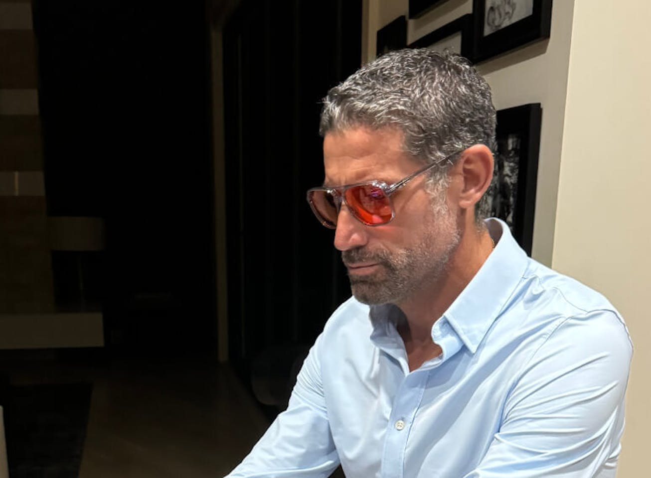 Man in blue shirt typing on keyboard in red lens glasses