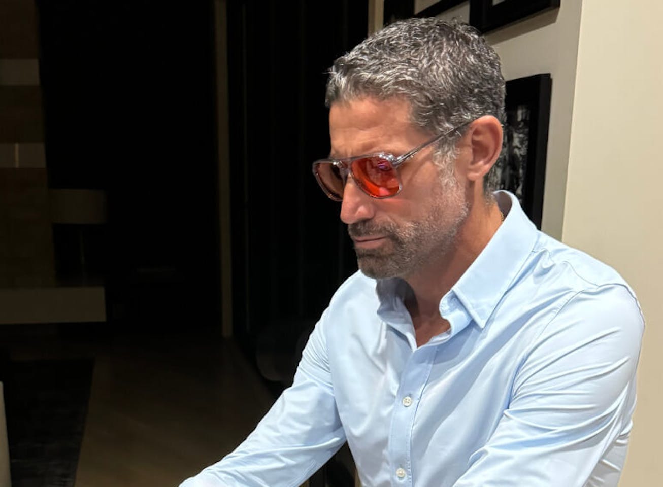 Man in blue shirt typing on keyboard in red lens glasses