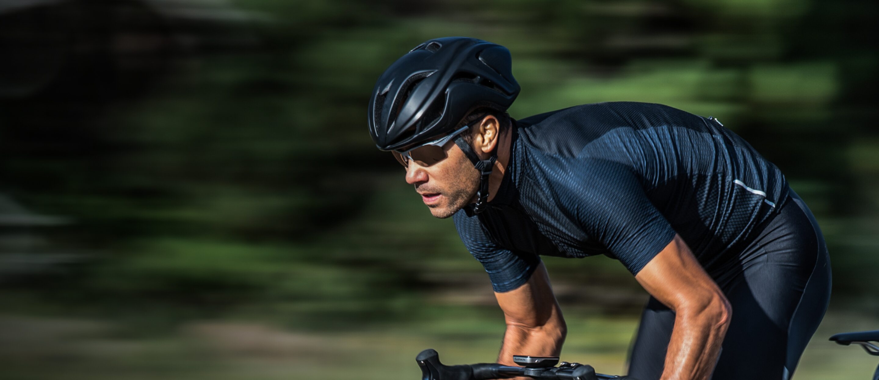Man in dark blue cycling gear riding bike