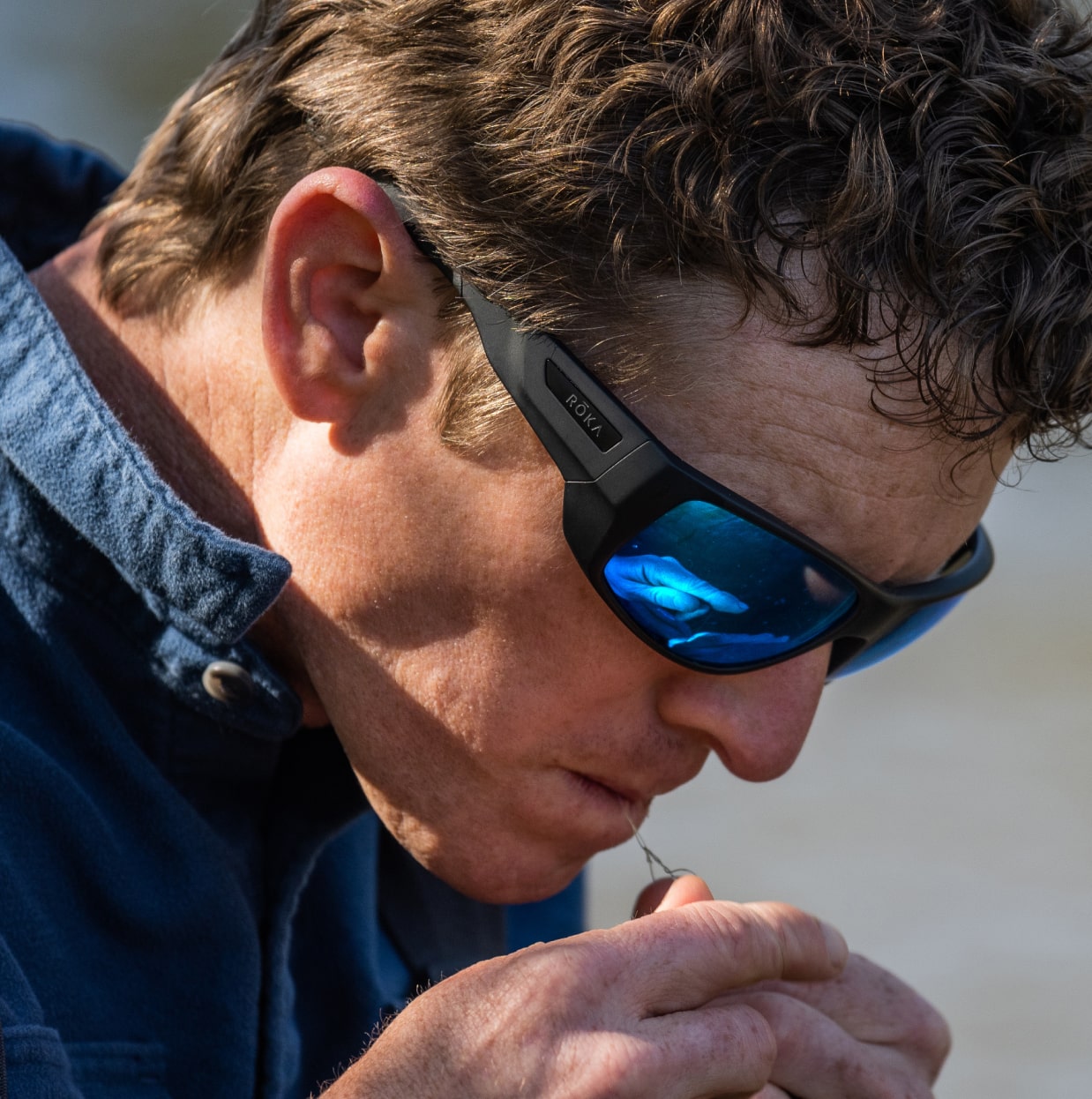 Man biting fishing line in AT-1 sunglasses