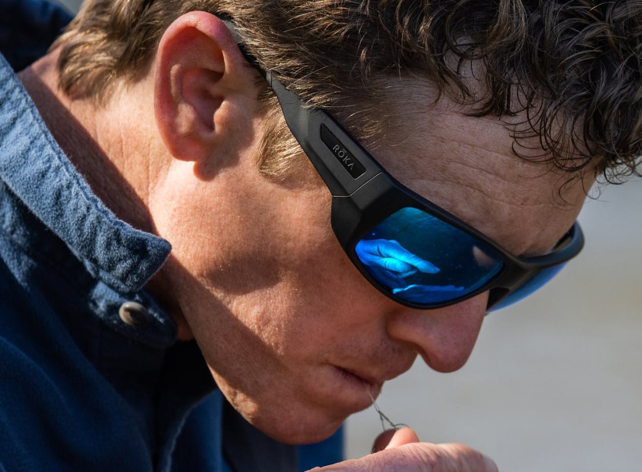 Man biting fishing line in AT-1 sunglasses