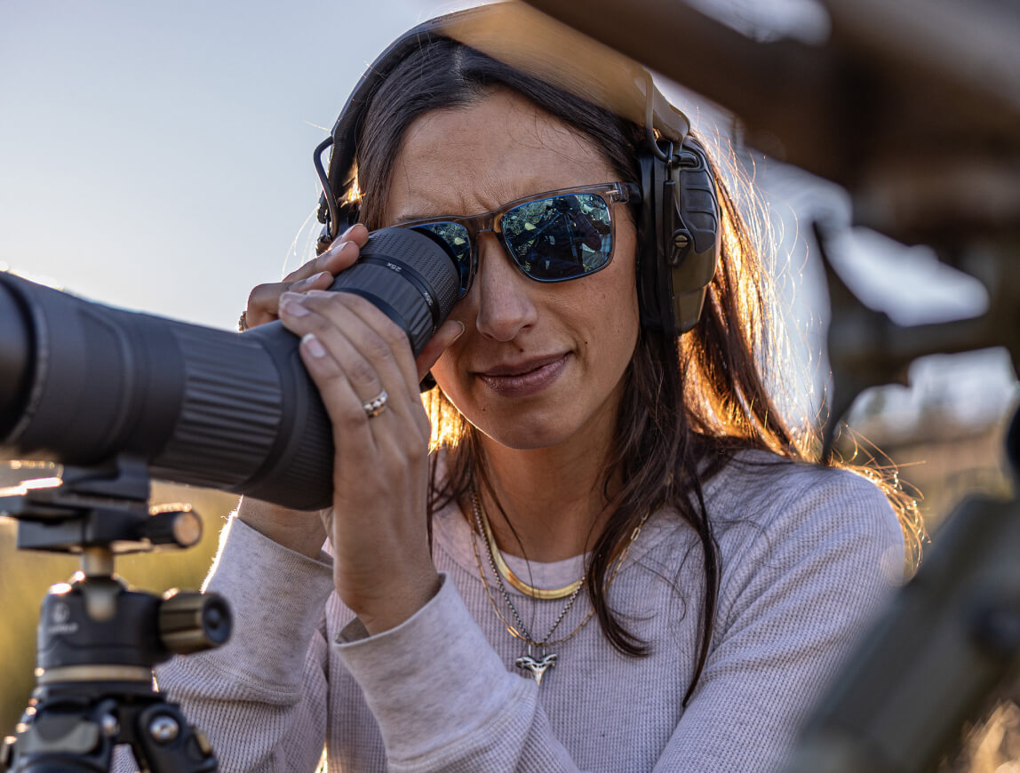 Woman looking through telescope in Barton sunglasses