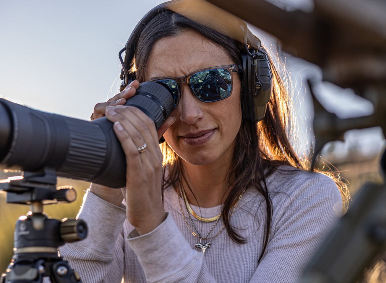 Woman looking through telescope in Barton sunglasses