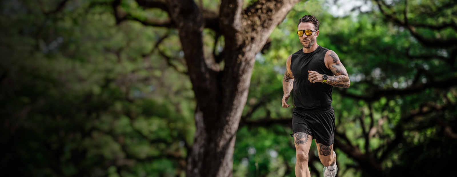 Man running in woods in gold Torino sunglasses