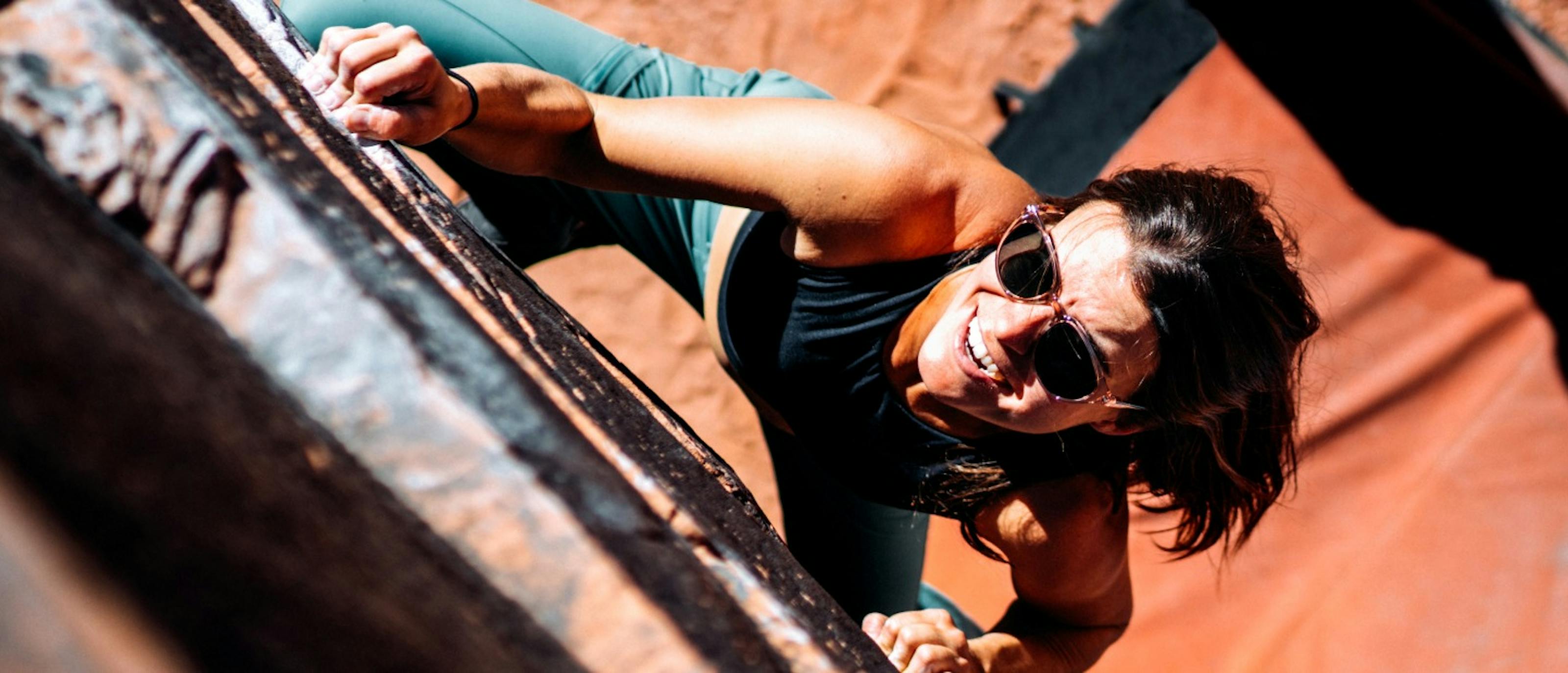 Woman bouldering outdoors in Lola sungasses