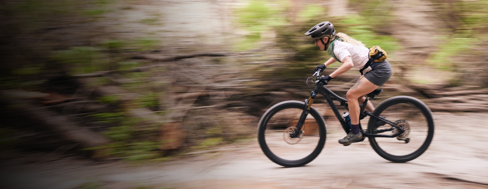 Woman mountain biking through woods