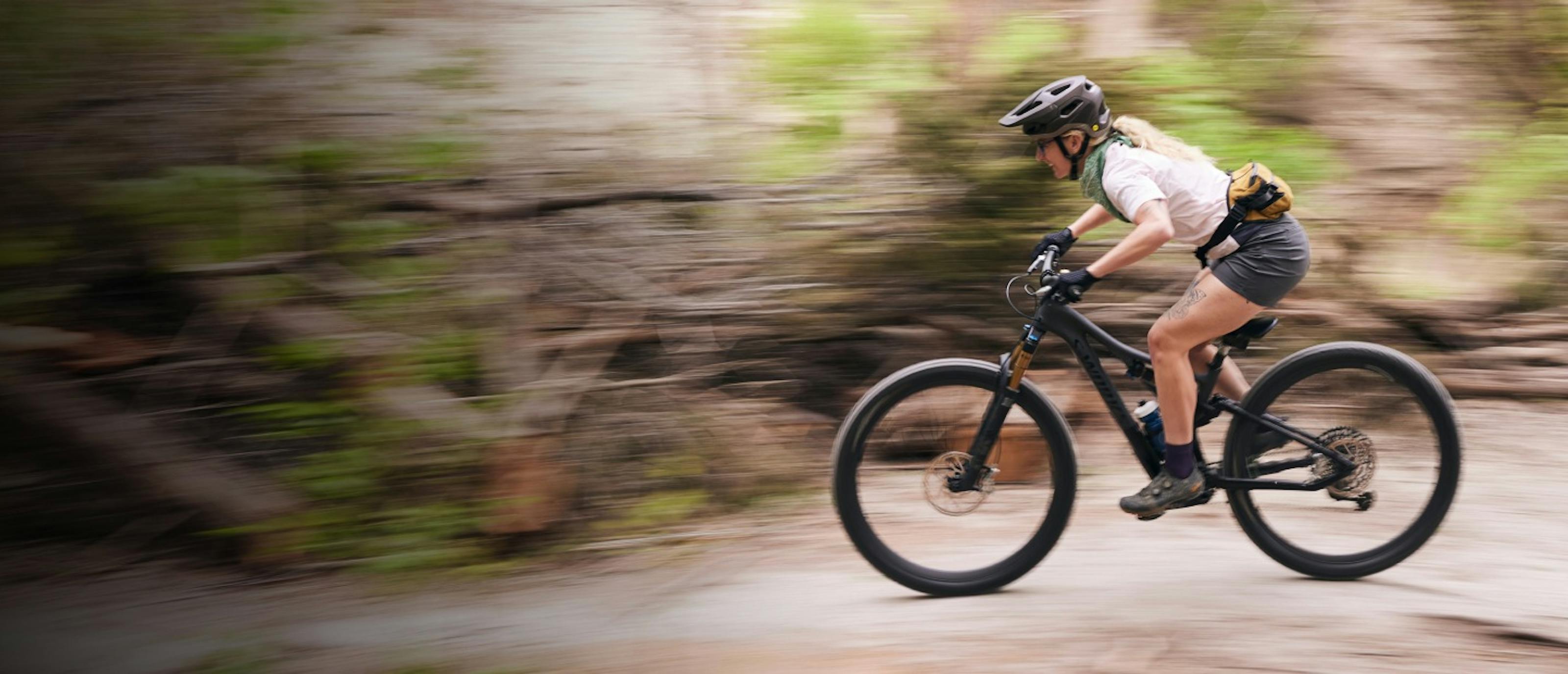 Woman mountain biking through woods