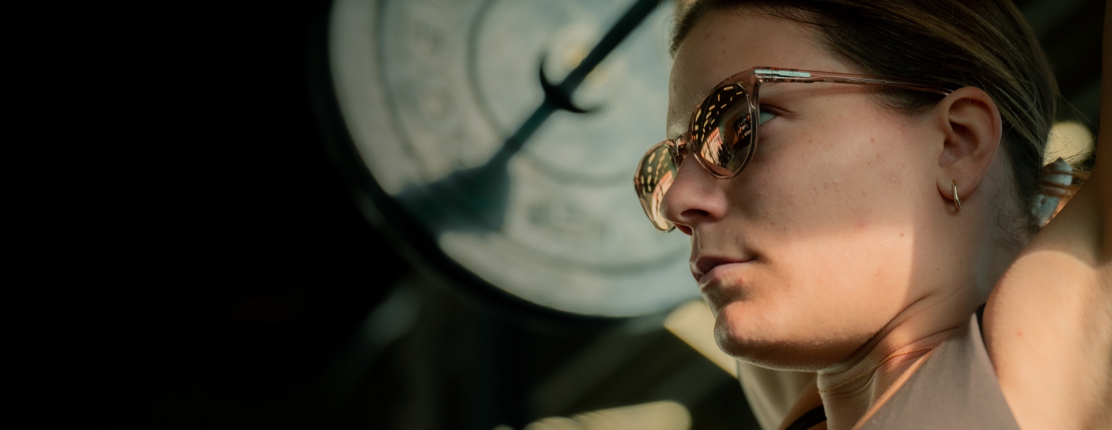 Woman lifting weights overhead in Lola sunglasses