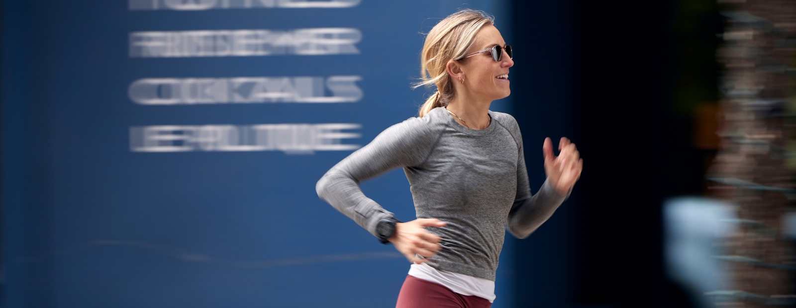 Woman running by building in cade sunglasses