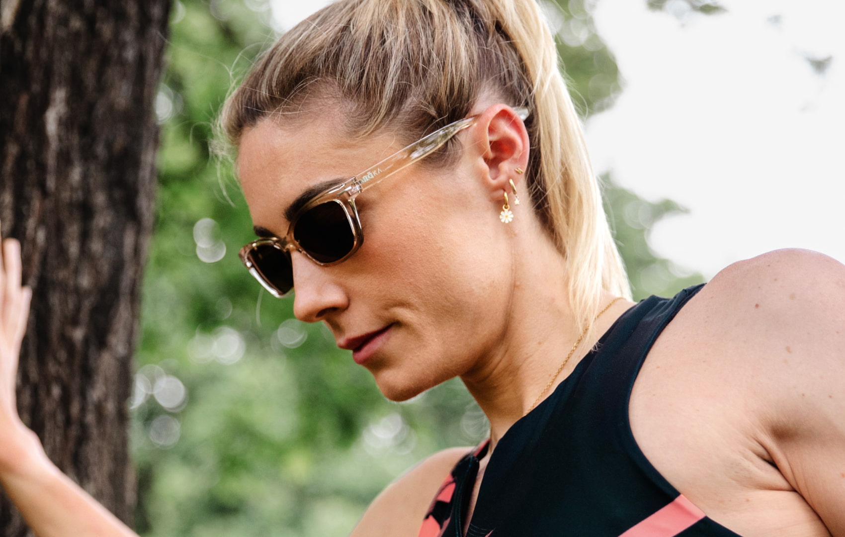 Woman stretching near tree wearing Siena sunglasses