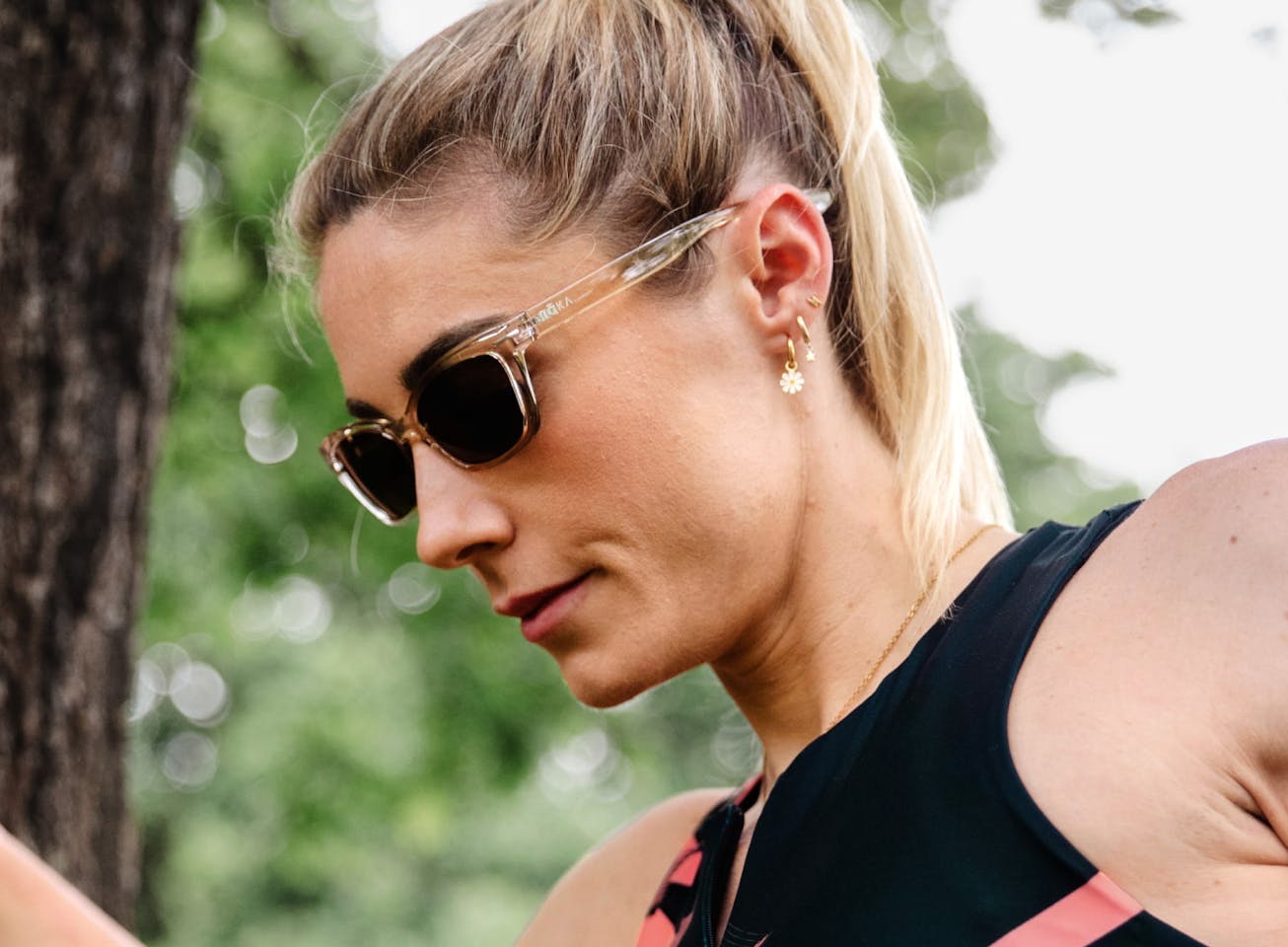 Woman stretching near tree wearing Siena sunglasses