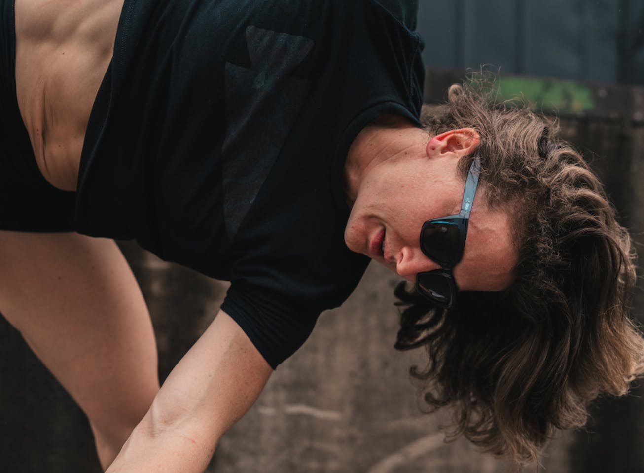 Woman bent over stretching wearing Marfa sunglasses