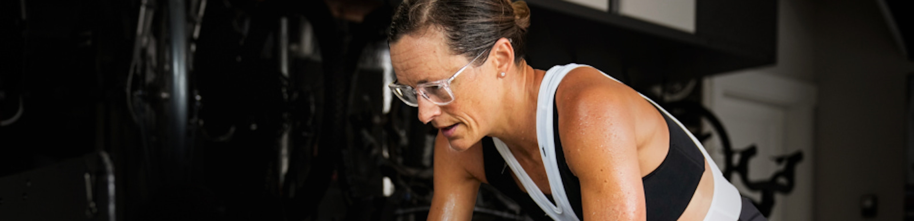 Woman riding stationary bike wearing ROKA eyeglasses