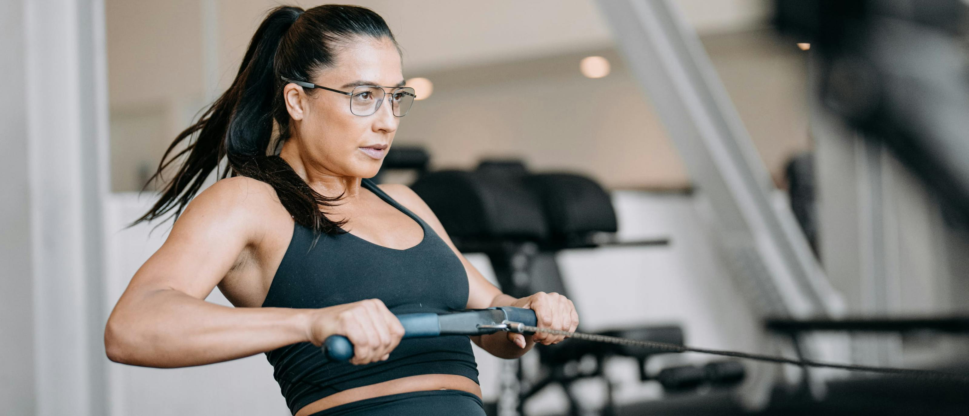 Woman in gym using rowing machine wearing Falcon Titanium eyeglasses