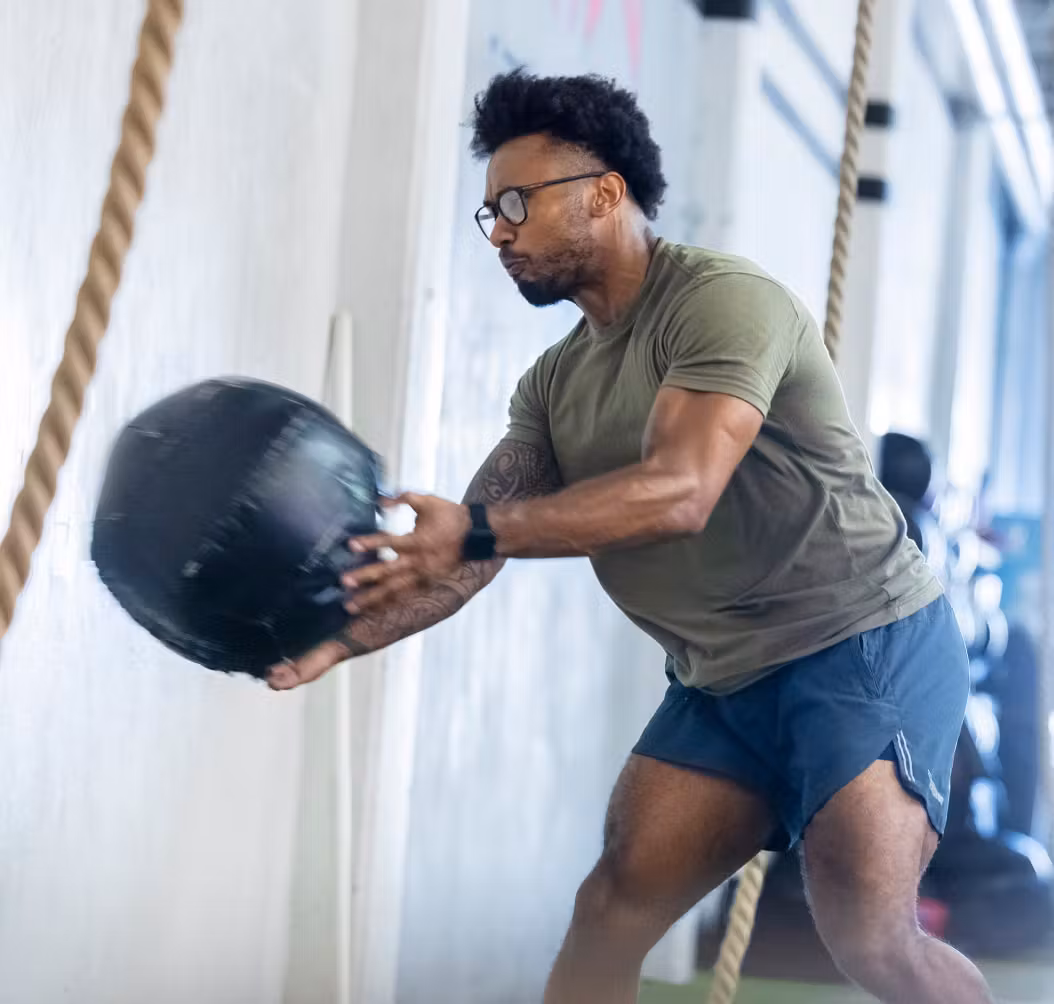 Man throwing medicine ball wearing rectangular, matte black Rory eyeglasses