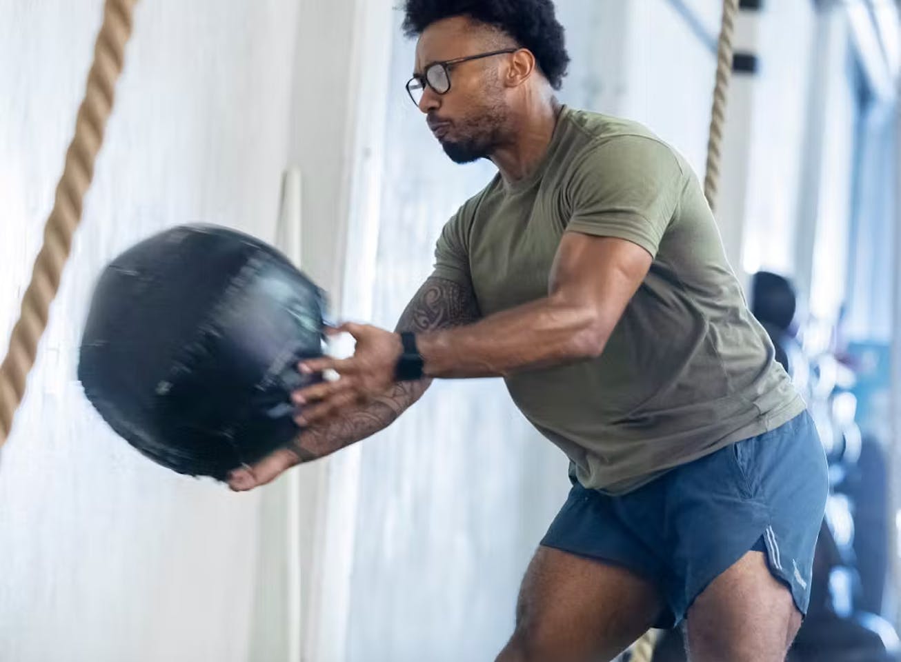 Man throwing medicine ball wearing rectangular, matte black Rory eyeglasses