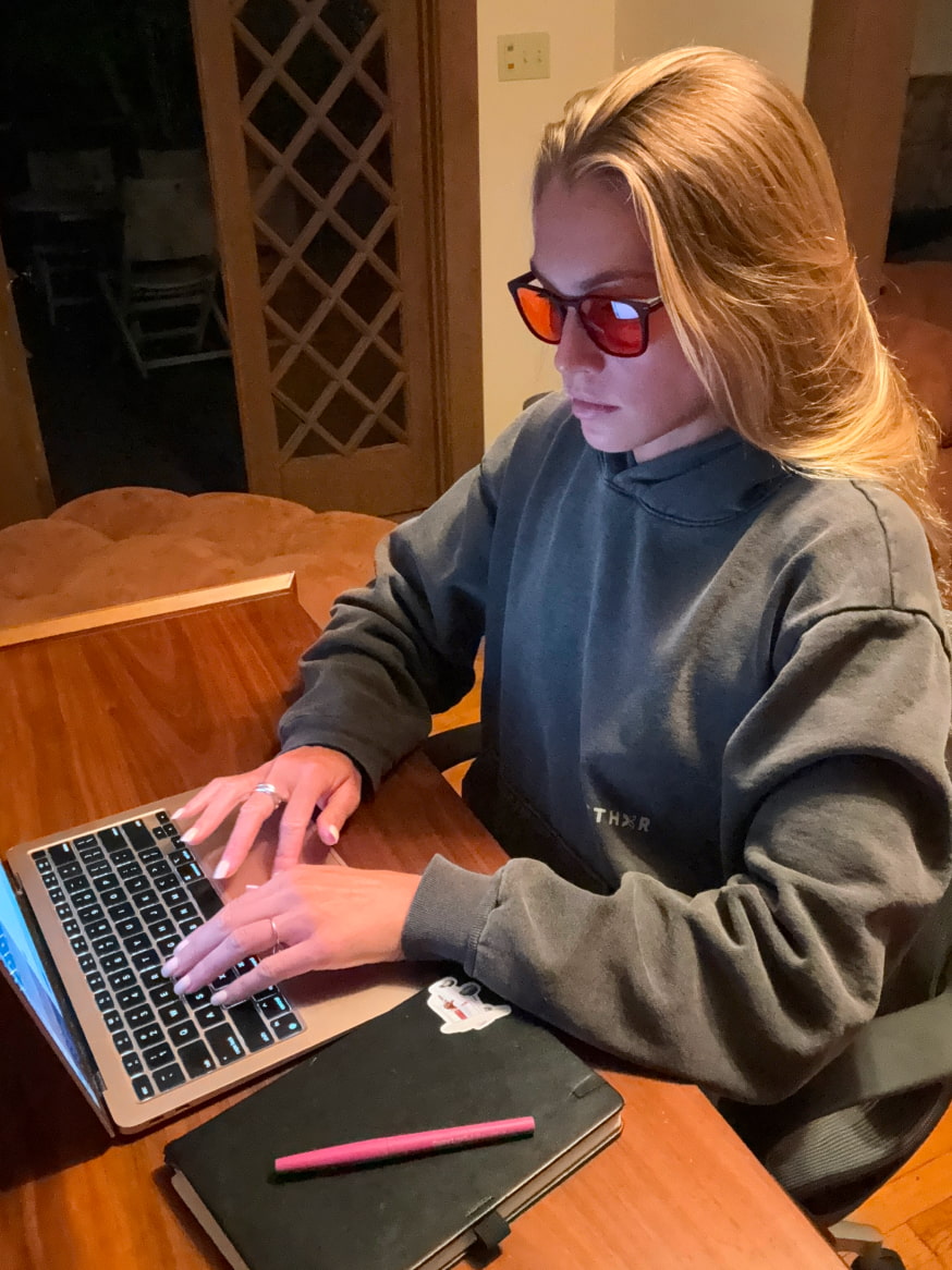 Woman at desk on laptop wearing Red Lens glasses