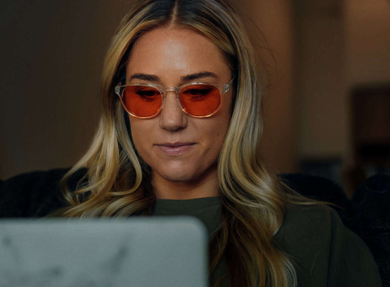 Blonde haired woman on laptop wearing Red Lens glasses
