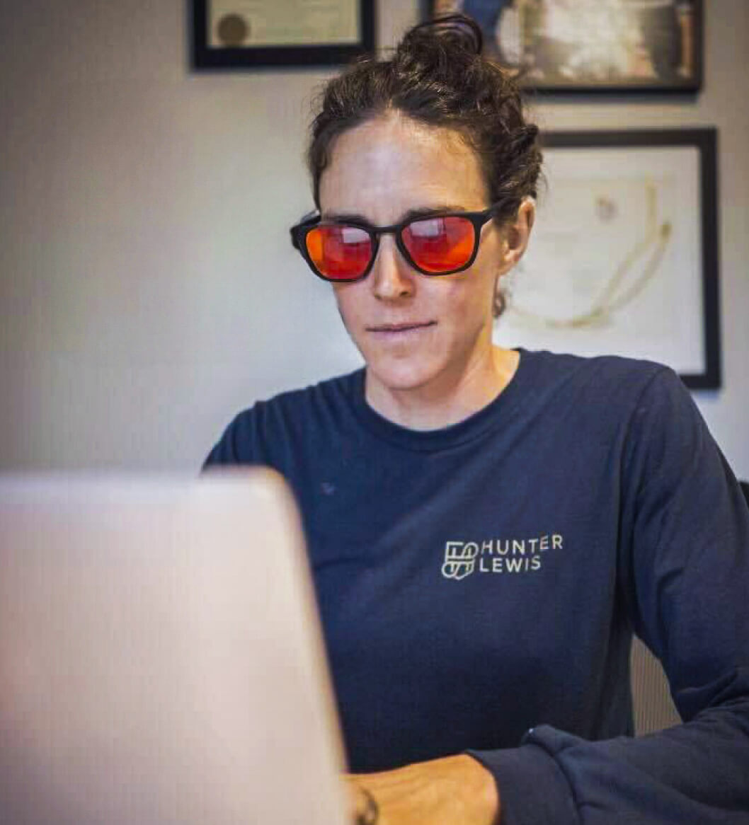 Woman on laptop wearing Red Lens glasses