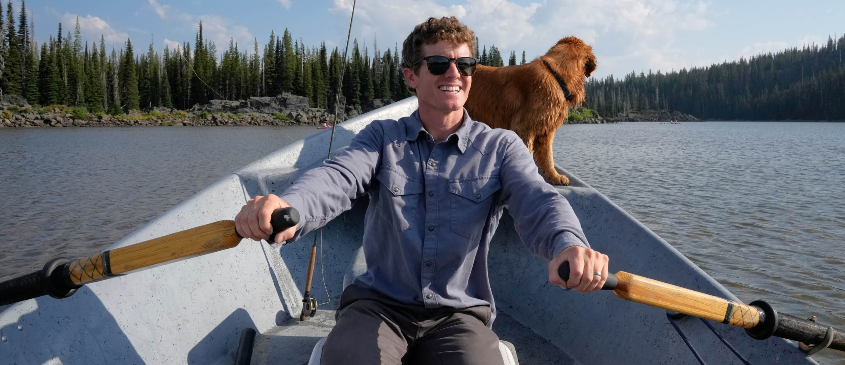 Man rowing boat with golden retriever
